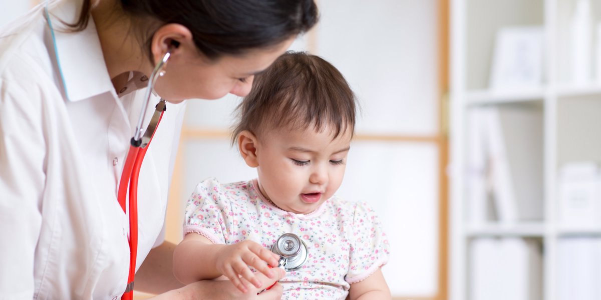 Kvinnlig läkare lyssnar på bebis hjärta