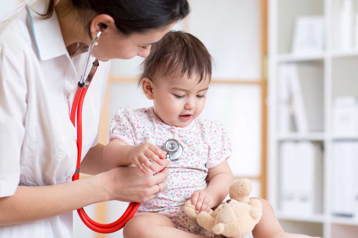 Kvinnlig läkare lyssnar på bebis hjärta